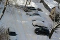 Snow-covered cars in the yard near the house and trees Royalty Free Stock Photo