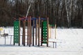snow-covered children's playground with a stairs and obstacles on edge of forest in winter