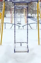 Snow-covered children`s swings. Winter landscape