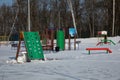 snow-covered children's playground with basketball hoop, stairs and obstacles in winter