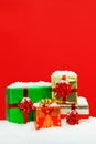 Snow covered Christmas presents red background. Royalty Free Stock Photo