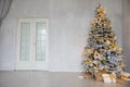 Snow-covered Christmas tree with gifts for the new year in the interior of a white room Royalty Free Stock Photo