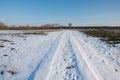 Snow-covered country road. Forest on the horizon and blue sky Royalty Free Stock Photo