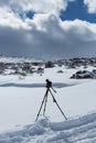Snow covered desert landscape with a camera and a tripod taking pictures of puffy clouds and blue sky Royalty Free Stock Photo