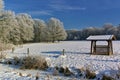 Snow-covered field with forest and fodder rack Royalty Free Stock Photo