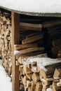 Snow-covered firewood stacked under a canopy, firewood for the winter. Winter landscape Royalty Free Stock Photo