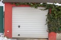 Snow-Covered Garage Door With Red Wall and Green Ivy Royalty Free Stock Photo