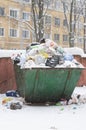 Snow-covered garbage container stuffed with plastic large bags