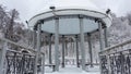 Snow-covered gazebo with a metal bridge in the middle of a lake in the park Royalty Free Stock Photo