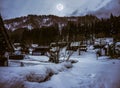 Snow covered ground in winter. Town with night sky and full moon Royalty Free Stock Photo