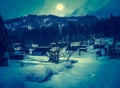 Snow covered ground in winter. Town with night sky and full moon Royalty Free Stock Photo