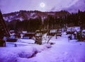 Snow covered ground in winter. Town with night sky and full moon Royalty Free Stock Photo