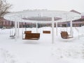 Snow-covered hanging swing in the snowfall in the city on a winter day. Royalty Free Stock Photo