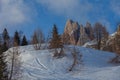 Snow-covered hill with larch and pine trees behind which Dolomite spiers emerge Royalty Free Stock Photo