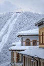 Snow covered hotel roofs of Gorky Gorod winter mountain resort with cableway lift on the background vertical scenery