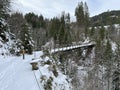 Snow-covered iron pedestrian bridge over the canyon of the Fallbach alpine stream at the foot of the Alpstein mountain range Royalty Free Stock Photo