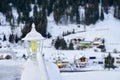 Snow covered lantern between two railings with Tyrol Alps ski resort on background.