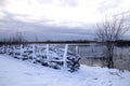 Snow-covered leeward fence by the lake on a cold winter day
