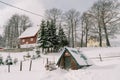 Snow-covered log shed next to a two-story house in the village Royalty Free Stock Photo