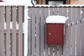 A snow-covered mailbox by a wooden fence, a snowy day Royalty Free Stock Photo
