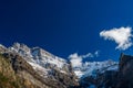 Snow-covered majestic mountain peaks with dark blue sky and flowing clouds. Royalty Free Stock Photo