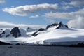 Snow covered mountain in Antarctica with inflatable boats in front Royalty Free Stock Photo