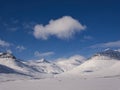 Snow-covered mountain landscape with single clouds