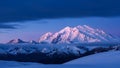 Snow-capped mountain range illuminated by soft pink and blue twilight light with dramatic clouds above Royalty Free Stock Photo