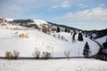 Snow-covered mountain slope with pine trees and a curvy road. Italian Alps Royalty Free Stock Photo