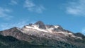 Snow covered mountain top under a blue sky with wispy clouds Royalty Free Stock Photo