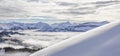 Snow covered mountains with inversion valley fog and trees shrouded in mist. Panoramic snowy winter landscape in Alps at