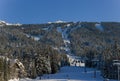 Snow covered mountains panorama - snowboarders and skiers ride on slopes and ski lifts. Ski resort in Whistler, Canada