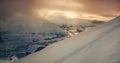 Snow covered mountainside, city below, and sunset sky above with clouds Royalty Free Stock Photo