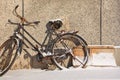 Snow covered old blakc bicycle parked against a textured wall, Changchun, China Royalty Free Stock Photo