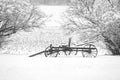 Snow-covered old wagon wheel cart set in the snow with a corn field in the background Royalty Free Stock Photo