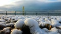 Snow covered pebble beach at sunrise on a frozen winters morning