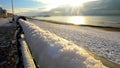 Snow covered pebble beach at sunrise on a frozen winters morning