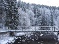 snow-covered pedestrian bridge over Elbe or Labe river and spruce tree forest at ski resort Spindleruv mlyn, Krkonose Royalty Free Stock Photo