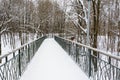 Snow-covered, pedestrian bridge over a ravine in the winter forest. Lots of snow on a beautiful road towards Royalty Free Stock Photo