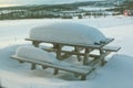 Snow covered picnic table in the garden of a mountain village house in the morning sun. The concept of a family holiday in the Royalty Free Stock Photo