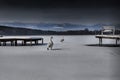 Snow covered pier near a lake, with swans wintertime in Diosjeno, Hungary Royalty Free Stock Photo