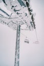 Snow-covered pillar of a four-seater chairlift with moving chairs