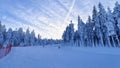 The snow-covered piste for skiers and snowboarders, equipped with snow cannons and safety fencing, runs under a chairlift through