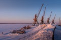 The snow-covered port cranes and snow piles on the frozen Pechora river bank at Naryan-Ma. Royalty Free Stock Photo