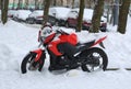 Snow-covered red motorcycle on the street Royalty Free Stock Photo