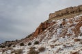 Snow covered red rock mountain with mesa plateau and brush with overcast sky