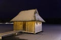 snow-covered reed roof wooden hut on a lake at the evening Royalty Free Stock Photo