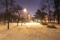 Snow covered roads in the night park with lanterns in the winter. Benches in the park during the winter season at night. Royalty Free Stock Photo