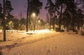 Snow covered roads in the night park with lanterns in the winter. Benches in the park during the winter season at night. Royalty Free Stock Photo