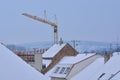 Snow-covered roofs with chimneys, antennas and tower crane. Royalty Free Stock Photo